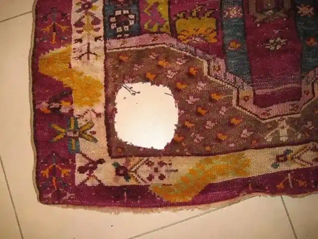 Antiek Turks vloerkleed met groot gat in het midden, voor reparatie.
