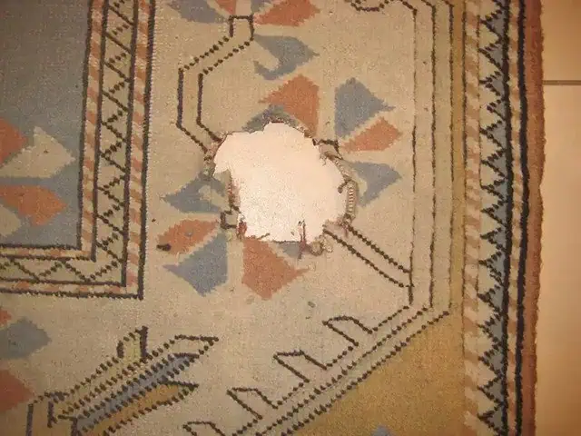 Turks Konya tapijt met groot gat, klaar voor vakkundige reparatie.