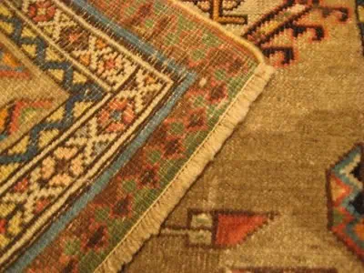 Gedetailleerde foto van de professionele restauratie van de katoenen franjes van een Perzisch tapijt, uitgevoerd in België.